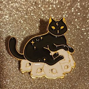 Black cat lapel pin sitting on a six mouse skulls.